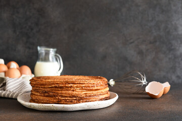 Stack of pancakes on the plate for breakfast. Pancake ingredients: milk, eggs, flour. Thin pancakes. Good morning.