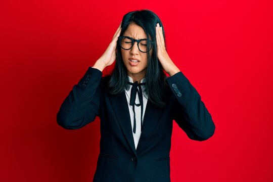 Beautiful asian young woman wearing business suit suffering from headache desperate and stressed because pain and migraine. hands on head.