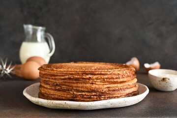 Stack of pancakes on the plate for breakfast. Pancake ingredients: milk, eggs, flour. Thin pancakes. Good morning.
