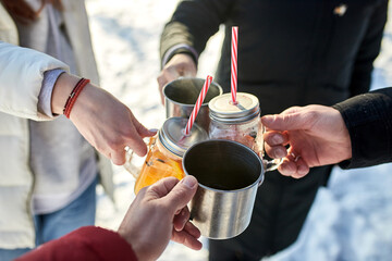 Close up image of group friends cheering with mulled wine in winter forest