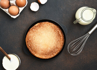 Cooking pancakes on a concrete background, top view. Pancake ingredients: milk, eggs, flour.
