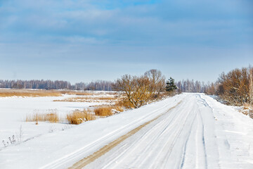 Obraz premium Snowy road along the lake on a sunny day