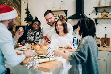 Cheerful group of friends together surfing mobile while enjoying New Year weekend at home