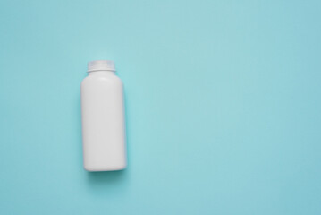 White plastic bottle on the blue flat lay background with copy space.
