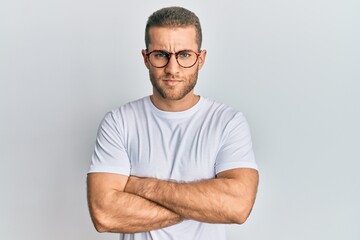 Young caucasian man wearing casual clothes and glasses skeptic and nervous, disapproving expression on face with crossed arms. negative person.