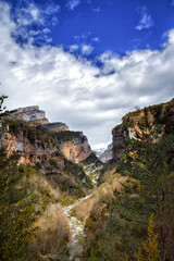 mountain scenery with a river flowing through it on a sunny day with cotton clouds, Anisclo canyon on the Bellos river, Huesca Pyrenees, Spain