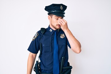 Young caucasian man wearing police uniform tired rubbing nose and eyes feeling fatigue and headache. stress and frustration concept.