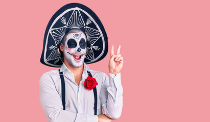 Man wearing day of the dead costume over background smiling with happy face winking at the camera...