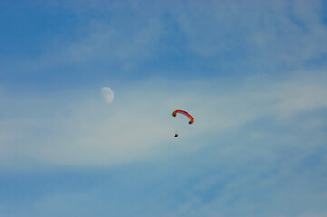 paraglider against the blue sky, the moon in the background