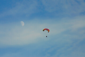 paraglider against the blue sky, the moon in the background