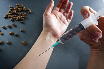 Grains of coffee and an injection syringe in female hands. Caffeine addiction concept.