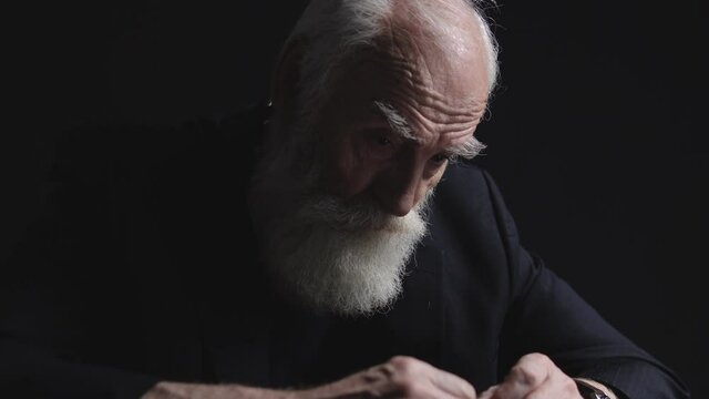 Sad aged businessman with grey beard sitting at office table, economic crisis