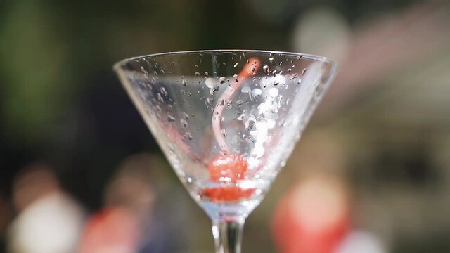 A beautiful cherry lies inside a glass of wine. Very nice close-up. Cool light