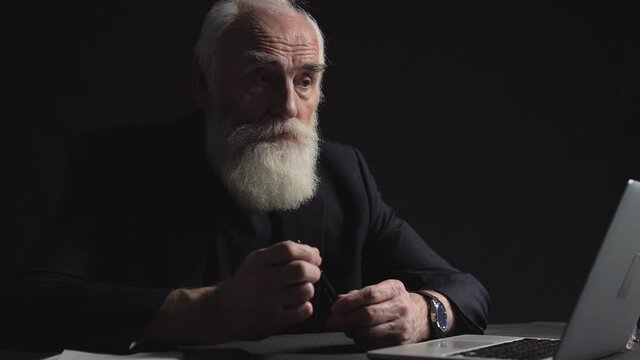 Mature business magnate feeling depressed, sitting at table, difficult decision