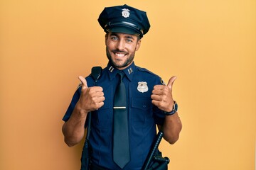 Handsome hispanic man wearing police uniform success sign doing positive gesture with hand, thumbs up smiling and happy. cheerful expression and winner gesture.