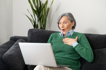 A surprised senior mature woman received exciting and positive news and cannot believe her eyes,...