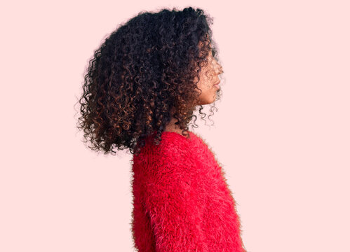 African American Child With Curly Hair Wearing Casual Winter Sweater Looking To Side, Relax Profile Pose With Natural Face With Confident Smile.