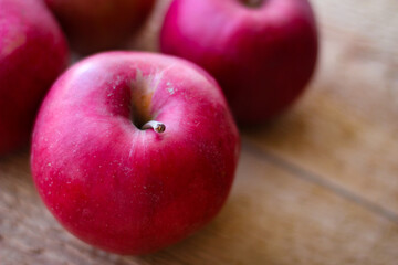 Red apples stand on a wooden surface