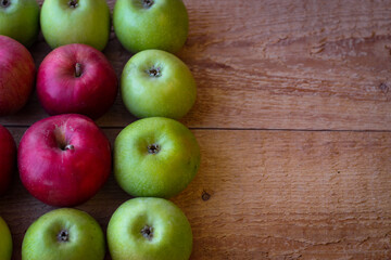 Green and red apples stand on a wooden surface