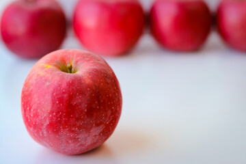 Red apples stand on a white surface