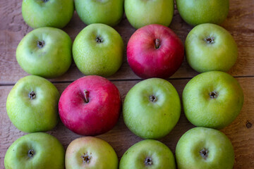 Green and red apples stand on a wooden surface