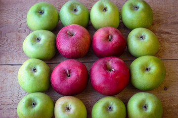 Green and red apples stand on a wooden surface
