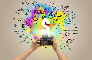 Close-up of a hand holding digital camera with abstract drawing and $ inscription