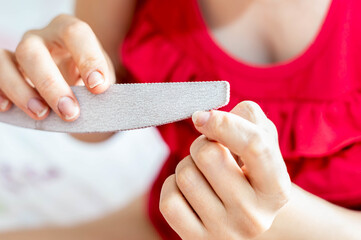 Closeup shot of a female using a nail file to align her nails at home