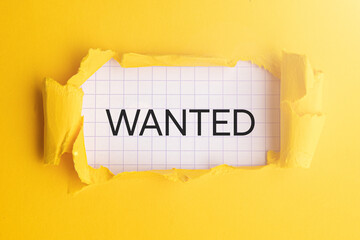 the words wanted are written on a piece of notebook paper on a yellow background