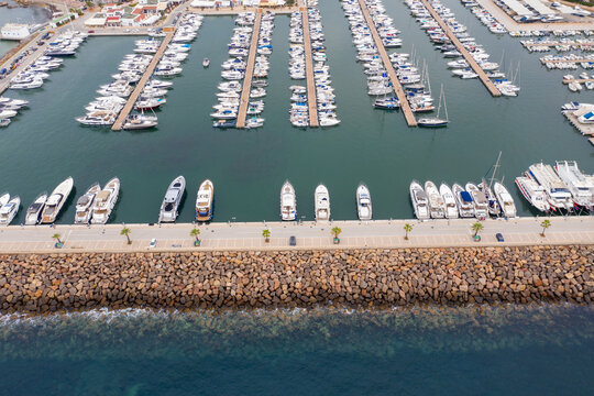 Aerial drone photo of the beautiful island of Ibiza in Spain showing the boating harbour with rows of speed and sail boats in the harbour on a bright sunny summers day