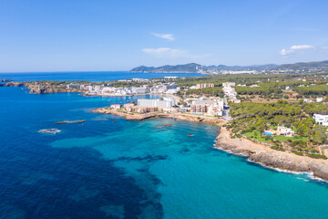 Fototapeta na wymiar Aerial drone photo of the beautiful island of Ibiza in Spain showing the costal front golden sandy beaches with people relaxing and sunbathing on a hot sunny summers day