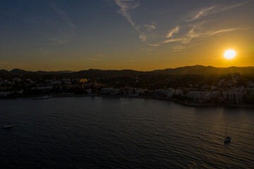 Aerial photo of the beautiful town of Ibiza in Spain showing the town at sunset with the sun setting behind the mountains along the boating harbour in Santa Eularia des Riu