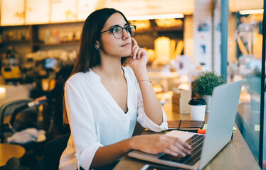 Pensive woman with laptop thinking about project in cafe