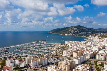 Fototapeta na wymiar Aerial photo of the beautiful island of Ibiza, Spain in the Balearic islands showing the beach and harbour area by the mediterranean sea in Santa Eularia des Riu on a bright sunny summers day