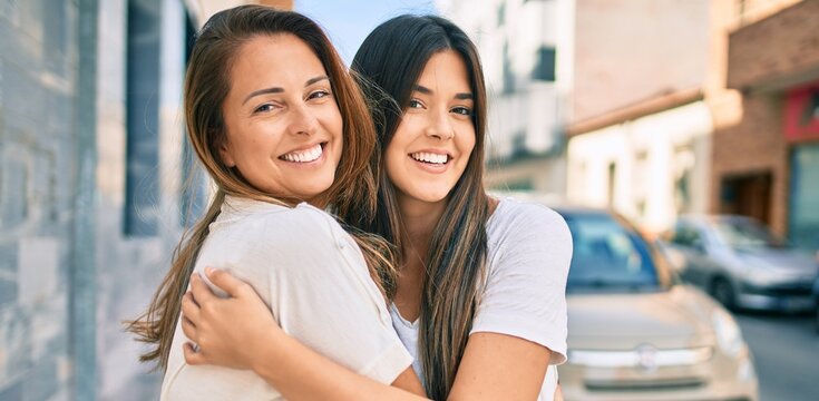 Beautiful hispanic mother and daughter smiling happy standing at the city.
