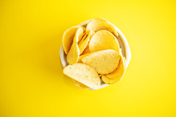Yellow potato chips with salt and season on a yellow background