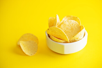 Yellow potato chips with salt and season on a yellow background