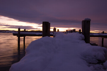 wooden snow covered pier with a stunning sunset in the background