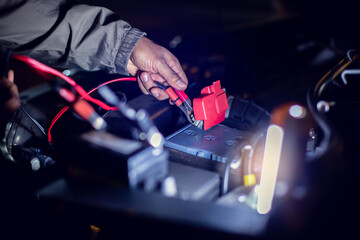 Selective focus to the mechanic's hand is connect cable to prepare replace the car battery. Delivery car maintenance on road or home. The concepts of car maintenance services in every location.