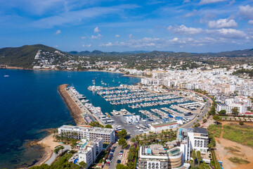 Obraz premium Aerial photo of the beautiful island of Ibiza, Spain in the Balearic islands showing the beach and harbour area by the mediterranean sea in Santa Eularia des Riu on a bright sunny summers day
