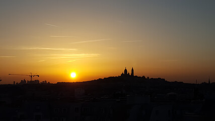 Relaxing sunset on a clear day in Paris. The colors of the sky shine in purple, red and orange. The silhouette of the church Sacre Coeur in Montmartre is in the background. 