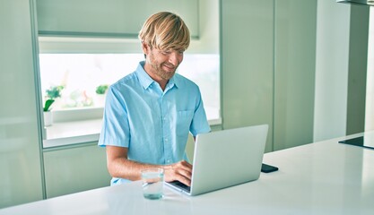 Young irish man smiling happy working using laptop sitting on the table at home.