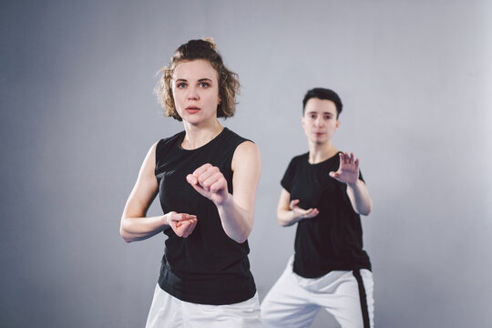 Coach Teaches Athlete To Hit Kick. Strong Female Martial Arts Athletes In Their Taekwon-do Training. Two Young Women Instructor And Student Practicing Basic Self Defense Skills At Gym