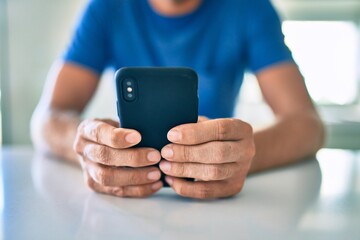 Young irish man smiling happy using smartphone sitting on the table at home.