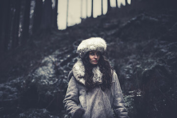 Fototapeta na wymiar Portrait of a woman wearing fur hat and leather jacket.Shot in forest surroundings.