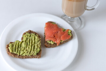 Sandwiches with avocado paste and salmon in the shape of heart, coffee