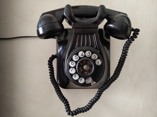 Old phone hanging on the wall. Black color. Vintage