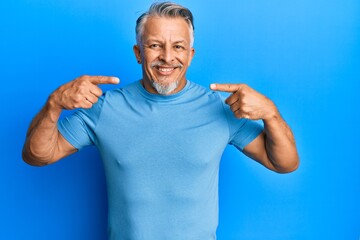 Fototapeta premium Middle age grey-haired man wearing casual clothes smiling cheerful showing and pointing with fingers teeth and mouth. dental health concept.