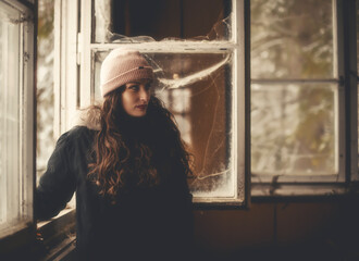 Portrait of a woman standing by the window in abandoned building.Urban exploration concept.