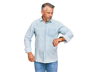 Fototapeta premium Middle age grey-haired man wearing casual clothes checking the time on wrist watch, relaxed and confident